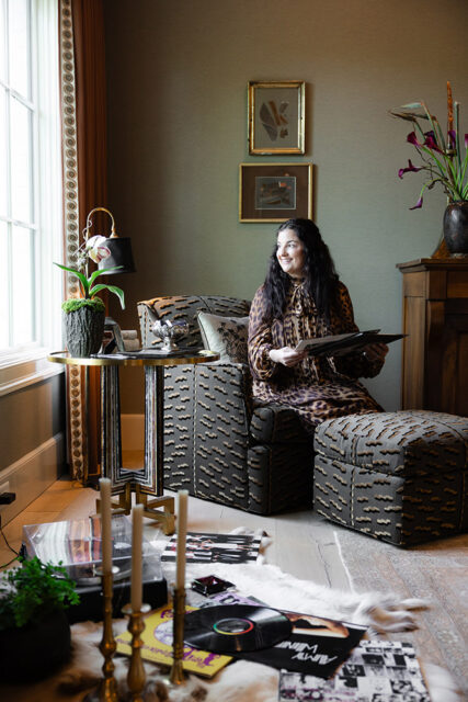 Woman in leopard print dress holding records in a room with patterned furniture