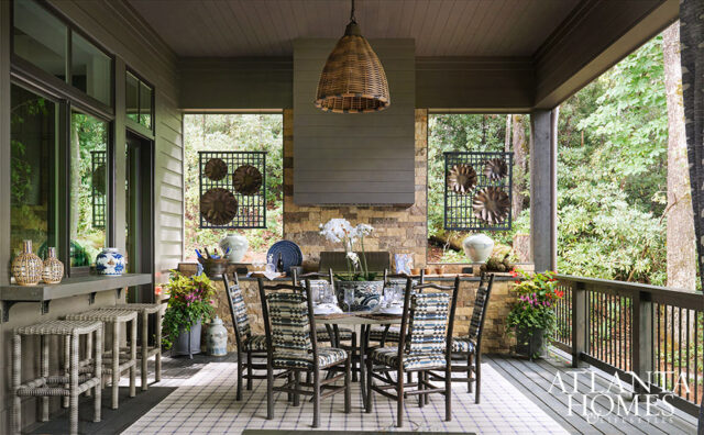 Covered porch with dining table, chairs, bar stools, and stone fireplace.
