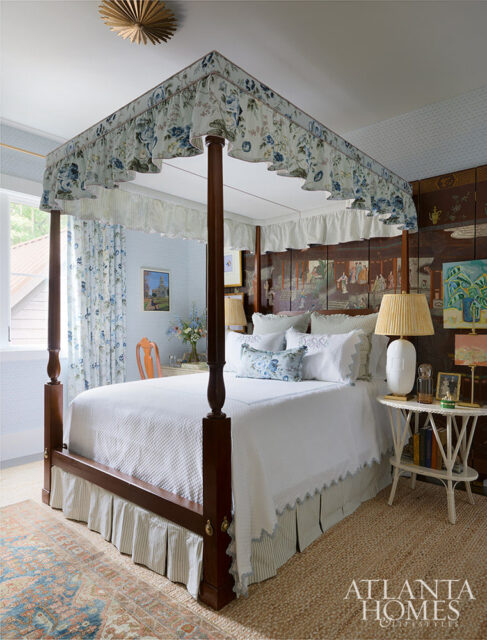 Bedroom with four-poster bed, floral canopy, white bedding, and chinoiserie screen