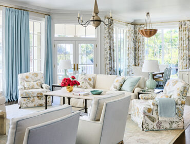 Living room with floral armchairs, light blue curtains, and a white sofa.