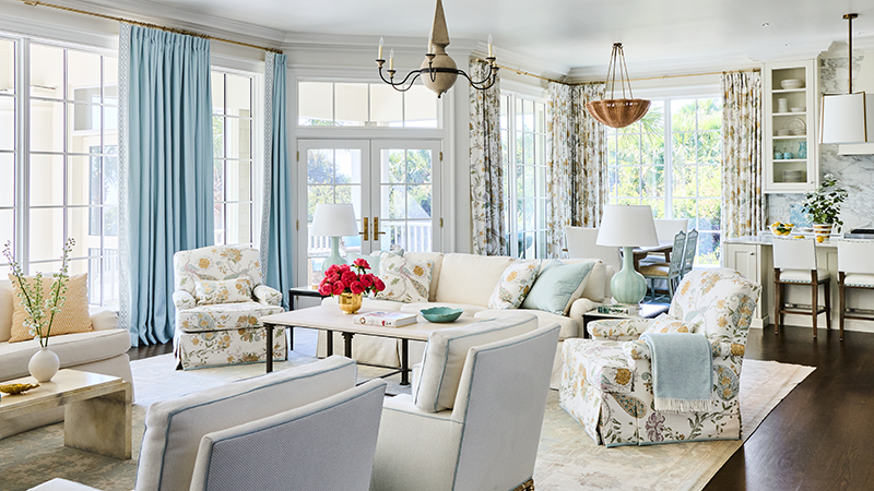 Living room with floral armchairs, light blue curtains, and a white sofa.