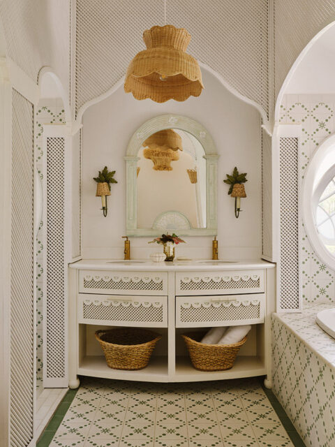 White bathroom vanity with rattan pendant light and green patterned tile floor