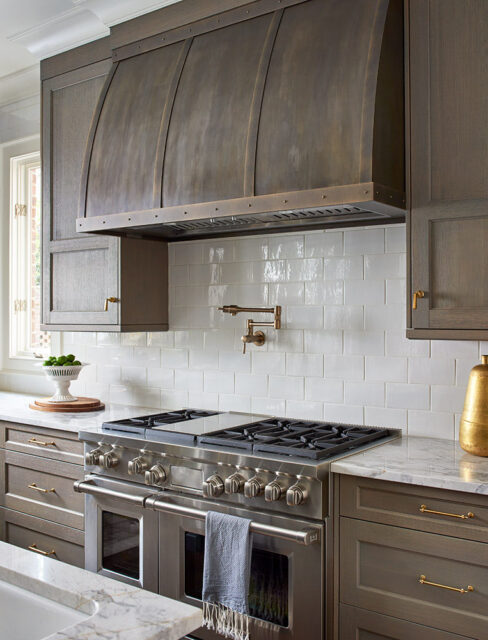 Kitchen with stainless steel range, white subway tile backsplash, and dark wood cabinets.