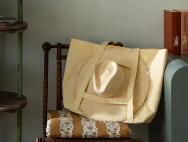 Wooden chair with striped floral cushion, straw hat, and yellow patterned tote bag