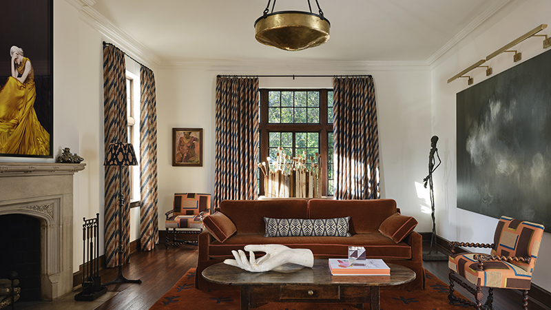 Living room with rust sofa, patterned chairs, fireplace, and large abstract art