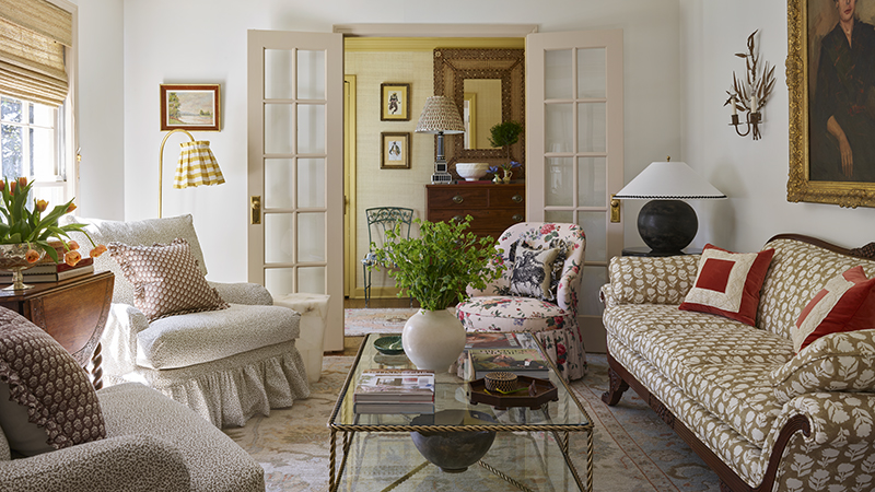 Living room with floral armchair, patterned sofa, and glass coffee table.
