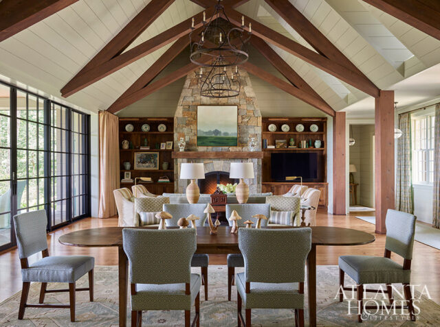Living room with vaulted wood beam ceiling, stone fireplace, and dining area.