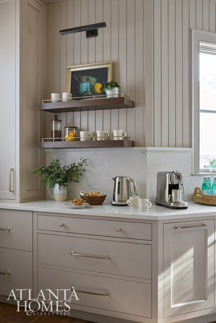 Kitchen with light gray cabinets, marble countertops, and paneled walls. Features a coffee maker