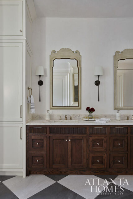 Bathroom with dark wood vanity, marble countertop, and two ornate mirrors.