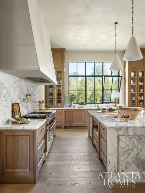 Kitchen with marble countertops, wood cabinetry, and large window overlooking trees.