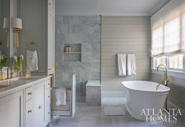 Gray bathroom with marble shower, freestanding tub, and double vanity with brass fixtures.