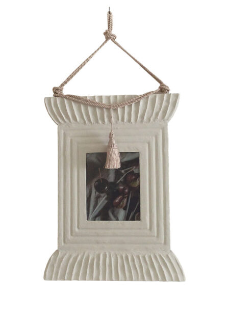 Cream-colored decorative frame with rope and tassel detail, showing still life painting
