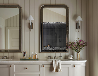 Neutral bathroom with double vanity, paneled walls, and two framed mirrors.