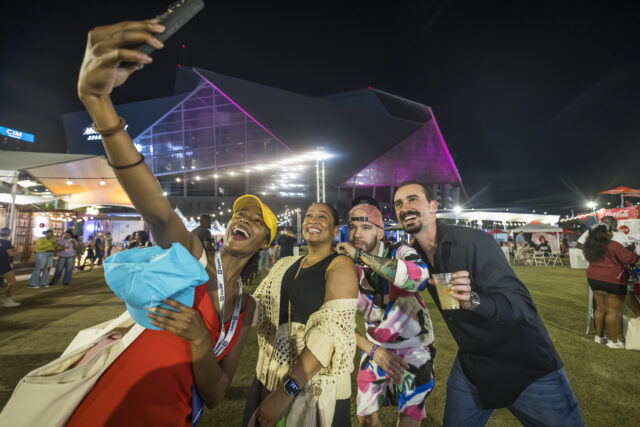 Four friends taking a selfie at night with a stadium in the background