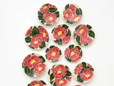 Collection of ceramic plates with hand-painted red flowers and green leaves