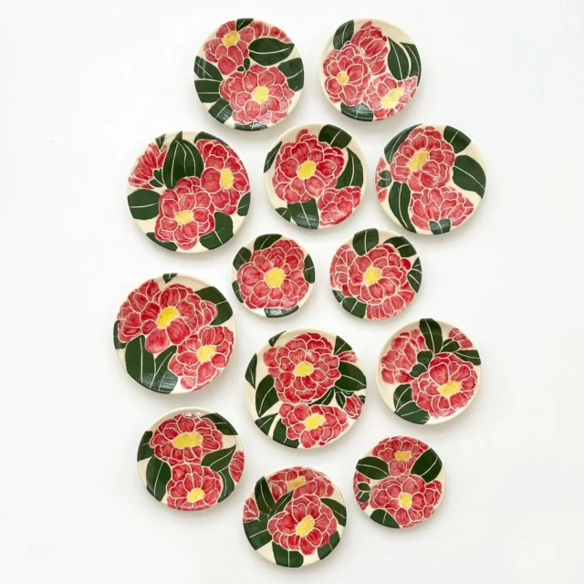 Collection of ceramic plates with hand-painted red flowers and green leaves